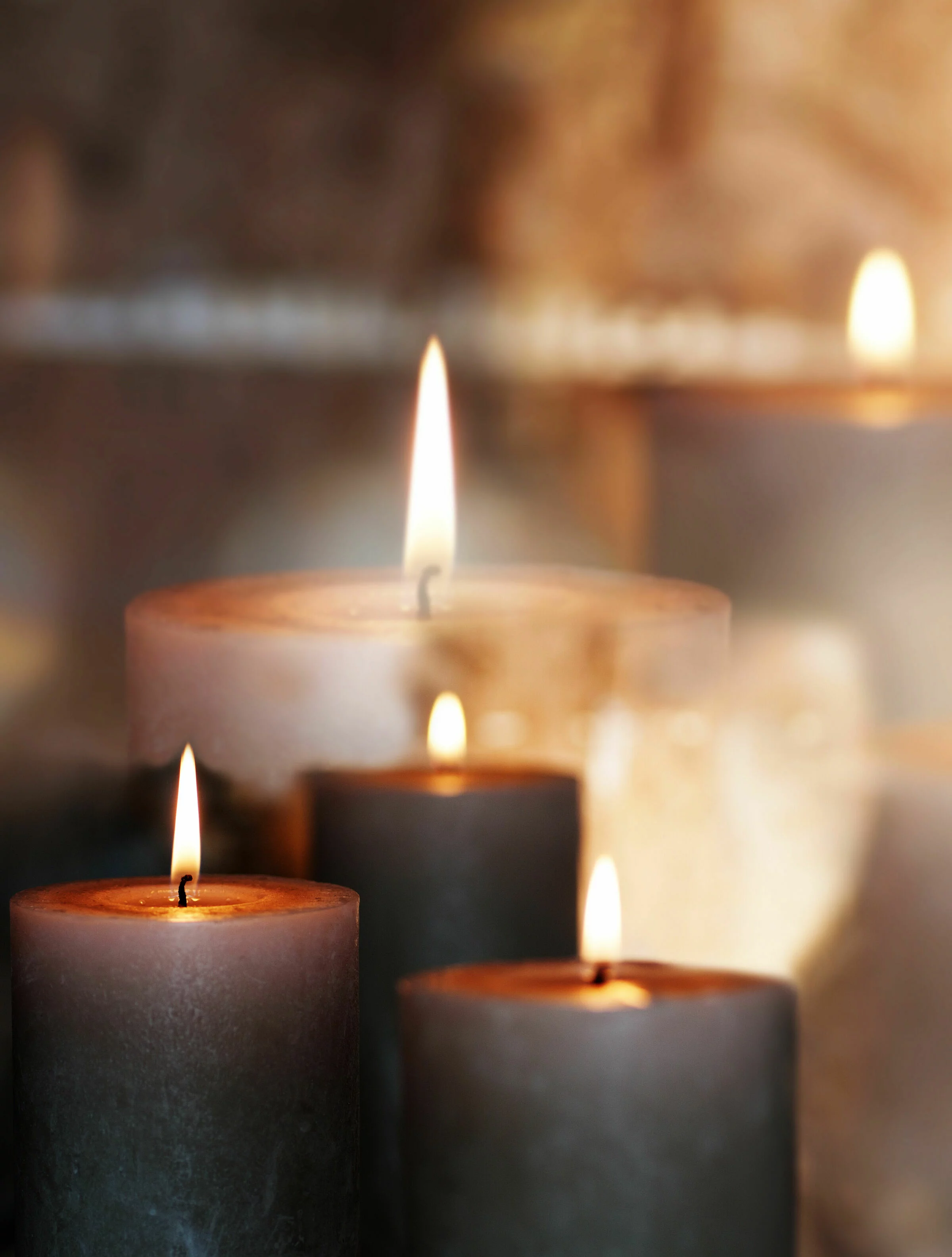 Brennende Kerzen stehen auf einer dunklen Oberfläche, mit warmem Licht, das in verschiedenen Größen angezündet wurde.